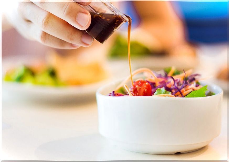 Pouring sauce over a salad bowl