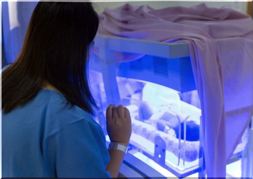 Woman next to an incubator with a baby.